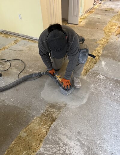 worker is using a floor sander on a concrete floor